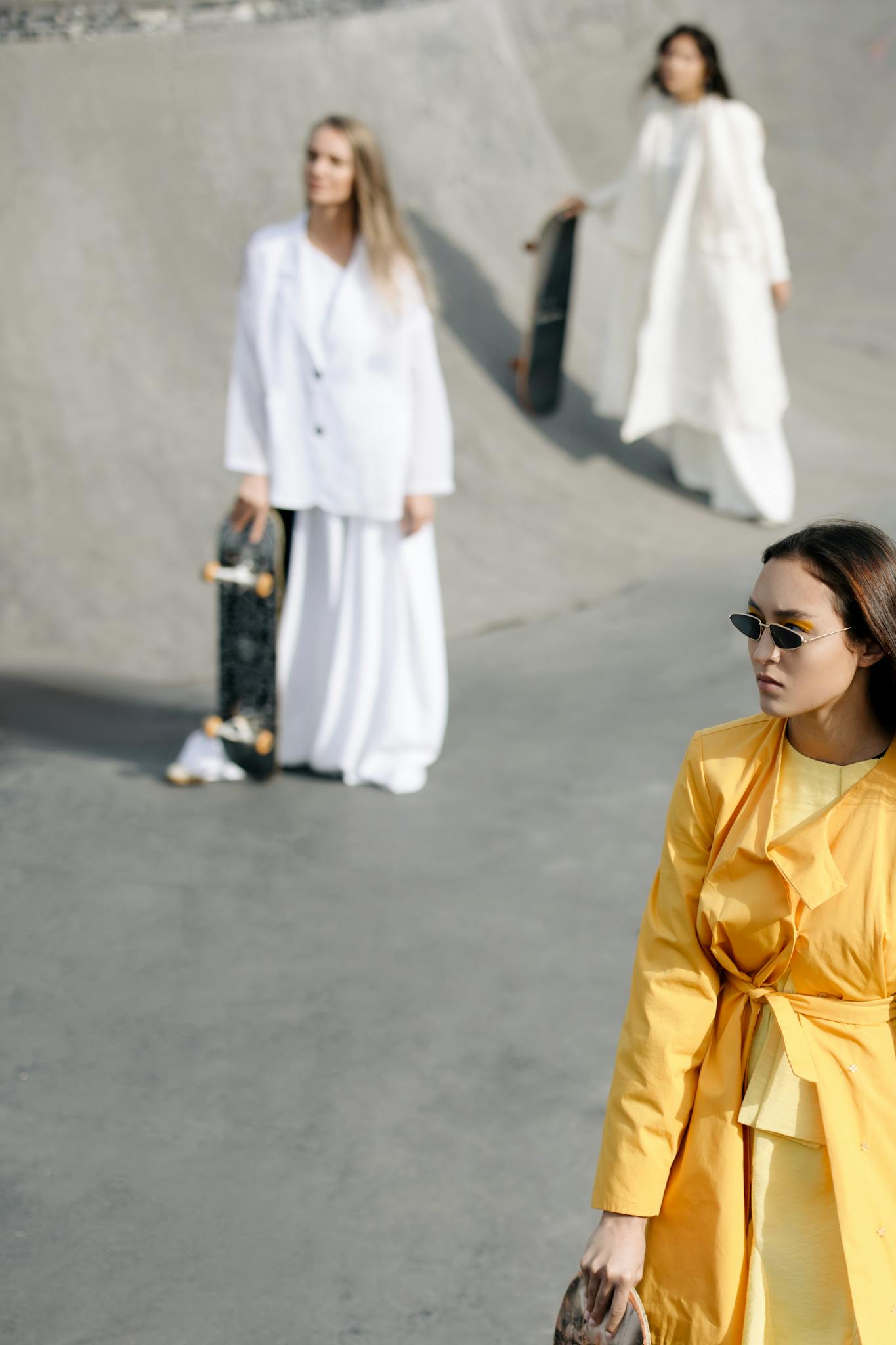 Elegant women in high fashion at a skate park showcase modern style and confidence.